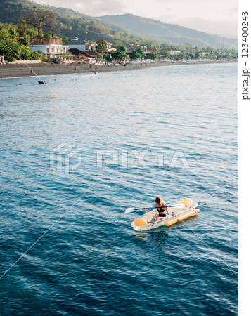 Woman on kayak swims in sea and view of coastal landscape. Drone view 123400243