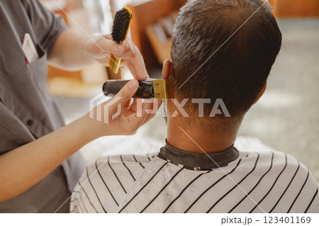 A skilled barber delivering a precise haircut in a contemporary and stylish salon environment 123401169
