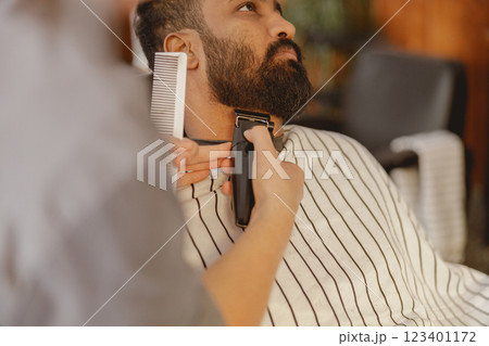 A Skilled Barber Elegantly Trimming a Stylish Beard at a Modern Salon Venue Today A Skilled Barber Elegantly Trimming a Stylish Beard at a Modern Salon Venue Today 123401172