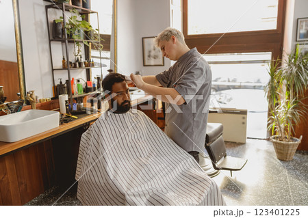 A skilled barber styling a clients hair within a chic, modern salon interior space 123401225
