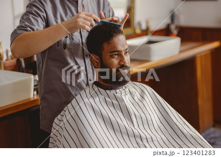 A skilled barber is precisely cutting a customers hair in a stylish, modern barbershop 123401283