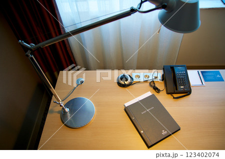 Mainz, Germany, July 8, 2017: Hotel Room Desk with Guest Directory, Lamp, and Telephone by Window 123402074