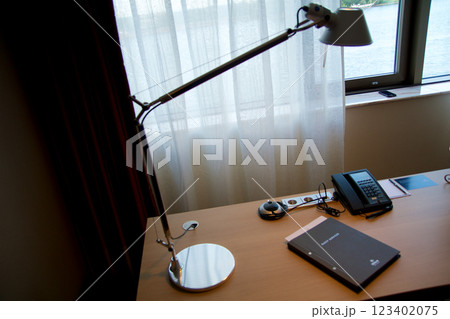 Mainz, Germany, July 8, 2017: Hotel Room Desk with Guest Directory, Lamp, and Telephone by Window 123402075