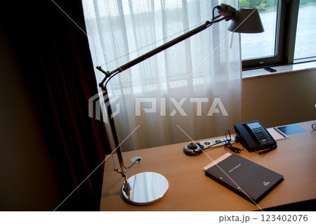 Mainz, Germany, July 8, 2017: Hotel Room Desk with Guest Directory, Lamp, and Telephone by Window 123402076