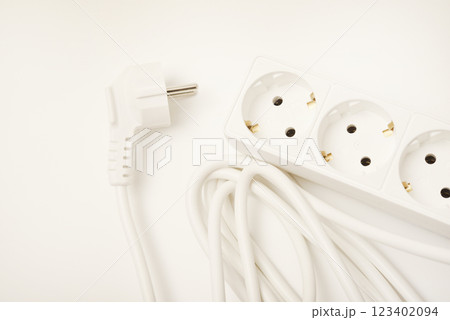 An extension cord with three sockets. White wire with sockets on a white background. 123402094