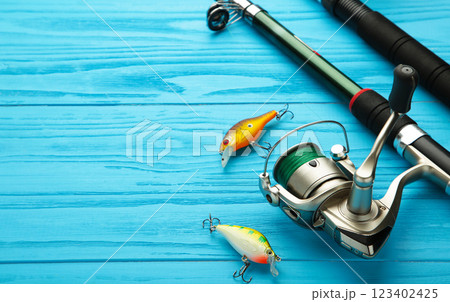 Nikolaev, Ukraine - 08 july, 2022: Fishing rods and spinnings in the composition with accessories for fishing on blue background. Nikolaev, Ukraine - 08 july, 2022: Fishing rods and spinnings in the composition with accessories for fishing on blue background. 123402425