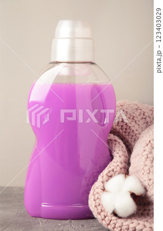 Eco washing concept. Laundry detergent, cotton flowers and pink sweater on grey background, copy space. Vertical photo Eco washing concept. Laundry detergent, cotton flowers and pink sweater on grey background, copy space. Vertical photo 123403029