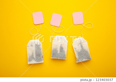 Tea bags with pink labels on yellow background. Minimalism, flat lay, place for text. Tea bags with pink labels on yellow background. Minimalism, flat lay, place for text. 123403037