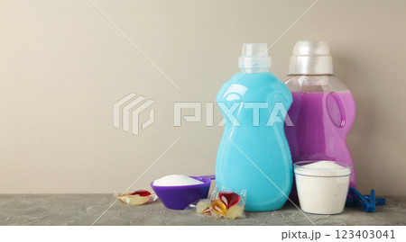 Laundry detergents with washing powder and capsules on grey background. Space for text Laundry detergents with washing powder and capsules on grey background. Space for text 123403041
