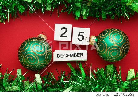 Wooden calendar with date of 25 december on red background with green christmas decoration Wooden calendar with date of 25 december on red background with green christmas decoration 123403055
