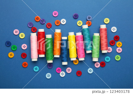 Colorful buttons with colorful thread on dark blue background Colorful buttons with colorful thread on dark blue background 123403178