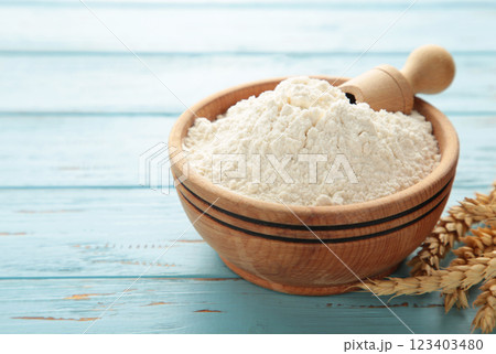 Wooden bowl with flour and flour spoon. Rice or wheat flour on blue wooden background. top view 123403480