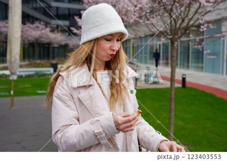 Chic outdoor snack: Woman with pretzel in blooming Prague park 123403553