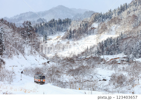 雪が積もる山を越え街に降りてきた大糸線の気動車 123403657