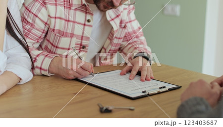 Close up happy family signing contract with professional realtor, after discussing agreement details. Couple putting signature, purchasing house and getting keys. Buying a rental property. Close up happy family signing contract with professional realtor, after discussing agreement details. Couple putting signature, purchasing house and getting keys. Buying a rental property. 123403687