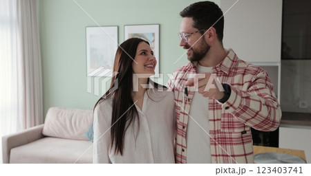 Happy couple owners of a new apartment show the key looking at the camera. Buying first family real estate, move in new home. Home buying concept. Happy couple owners of a new apartment show the key looking at the camera. Buying first family real estate, move in new home. Home buying concept. 123403741