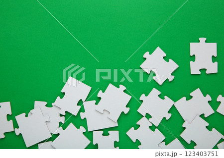 Unfinished white jigsaw puzzle pieces on green background 123403751
