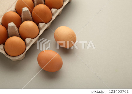 Chicken eggs in an open egg carton on grey. Top view with copy space. Natural healthy food and organic farming concept. Chicken eggs in an open egg carton on grey. Top view with copy space. Natural healthy food and organic farming concept. 123403761