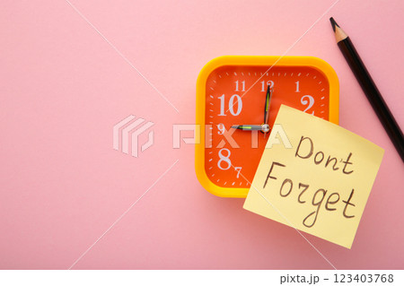 Alarm clock and reminder note with phrase Don't forget on pink background Alarm clock and reminder note with phrase Don't forget on pink background 123403768