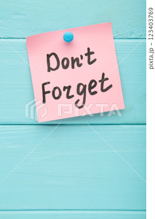 Reminder with text 'Don't forget' on a pink memo on blue background Reminder with text 'Don't forget' on a pink memo on blue background 123403769
