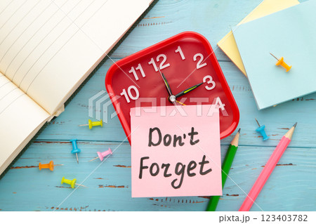 Alarm clock and reminder note with phrase Don't forget on light blue background Alarm clock and reminder note with phrase Don't forget on light blue background 123403782