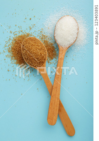 White and brown sugar in wood spoon on blue background. 123403891