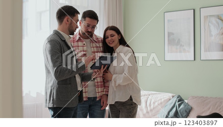 Male real estate agent showing young couple apartment plan using electronic tablet. Home buying concept. 123403897
