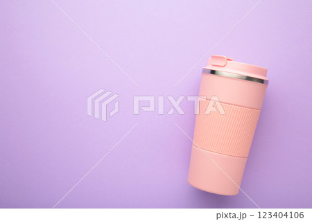 Pink thermo cup or thermos mug for tea or coffee on purple background. Hot beverage Pink thermo cup or thermos mug for tea or coffee on purple background. Hot beverage 123404106