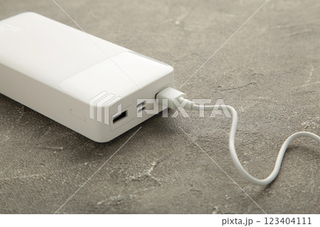 Portable powerbank with usb cable on grey background. 123404111