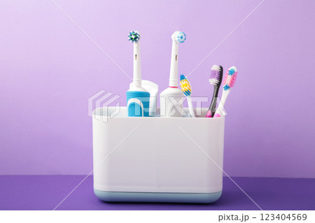 Holder with modern electric toothbrushes on purple background Holder with modern electric toothbrushes on purple background 123404569