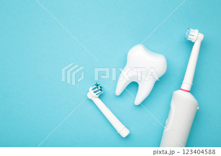 Modern electric toothbrush with tooth model on blue background. Controlled tool for daily oral care. Modern electric toothbrush with tooth model on blue background. Controlled tool for daily oral care. 123404588