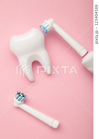 Modern electric toothbrush with tooth model on pink background. Controlled tool for daily oral care. Modern electric toothbrush with tooth model on pink background. Controlled tool for daily oral care. 123404589