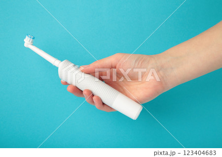 Woman holding electric toothbrush on blue background 123404683