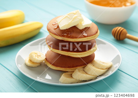 Plate with yummy banana pancakes on blue background. 123404698