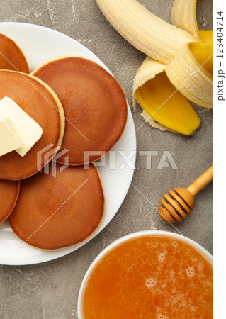Plate with yummy banana pancakes on grey background. Vertical photo 123404714