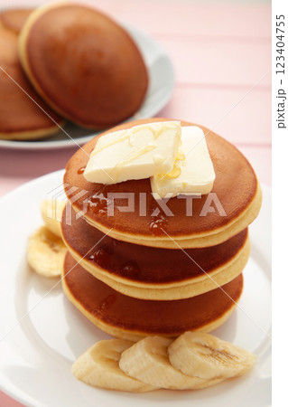 Plate with yummy banana pancakes on pink background. Vertical photo 123404755