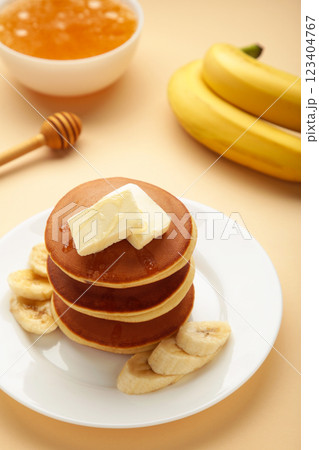 Plate with yummy banana pancakes on beige background. Vertical photo 123404767