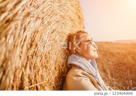 Smiling Woman Resting Against Hay Bale 123404909