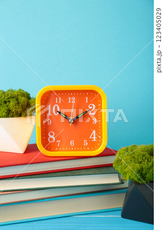 Front view desk with clock, books and plant on a table blue wall. Copy space Front view desk with clock, books and plant on a table blue wall. Copy space 123405029