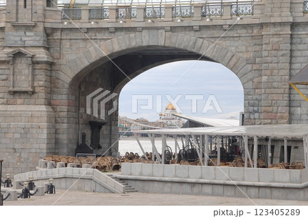 Cafe tables under the arch of the Crimean bridge overlooking the Temple, Moscow, June 2022. 123405289