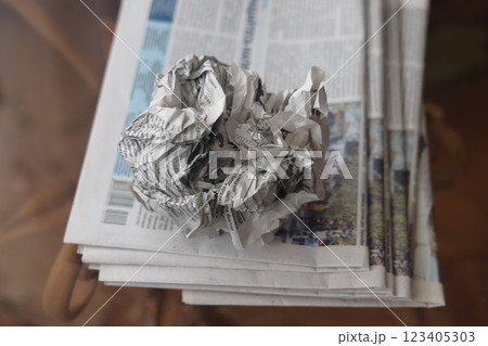 A crumpled sheet of newspaper lies on a stack of fresh newspapers, fake news, corrupt journalism. 123405303