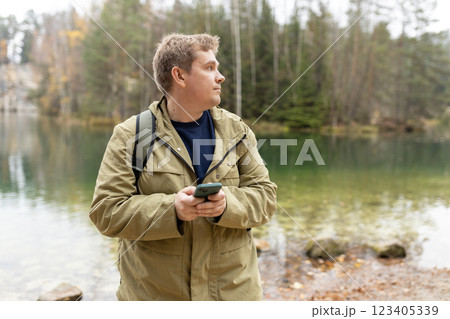 Travel backpacker standing with phone near the majestic lake. Travel, adventure. Concept of an active lifestyle. High quality photo 123405339