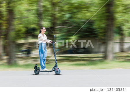 電動キックボードで爽やかに走る若い女性 123405854