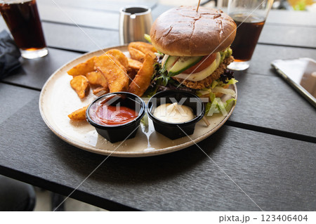 Plate with burger and french fries, ketchup and mayonnaise and cola on the table. 123406404