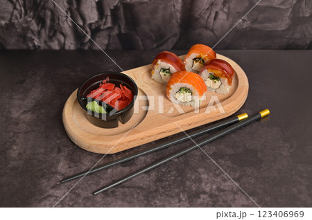 Set of sushi roll with rice and fish, wasabi and ginger on wooden serving board. Black chopsticks. Dark texture background with copy space. Japan menu. Asian food 123406969