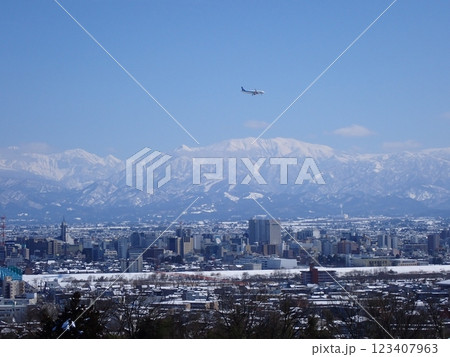 冠雪の北アルプス薬師岳を背景に雪景色の富山市街地と着陸態勢の旅客機 冠雪の北アルプス薬師岳を背景に雪景色の富山市街地と着陸態勢の旅客機 123407963
