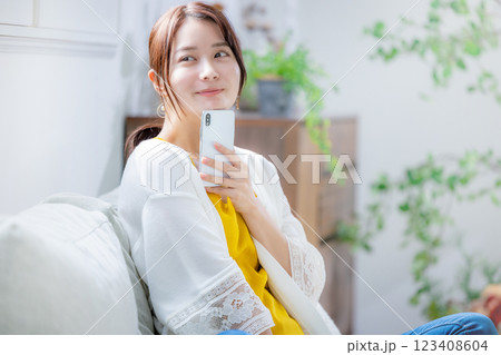 ソファに座ってスマホを見る女性 123408604