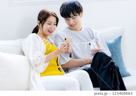 リビングでスマホを見る若い夫婦 リビングでスマホを見る若い夫婦 123408663