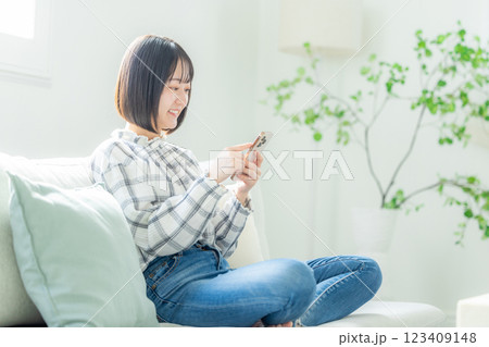 スマホを持ってソファでくつろぐ若い女性 123409148