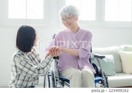 リビングで団らんする車椅子の祖母と孫娘 リビングで団らんする車椅子の祖母と孫娘 123409162